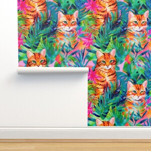 May include: A seamless pattern featuring orange tabby cats with green eyes peeking out from lush tropical foliage. The background is a vibrant pink with bright green, blue, and pink leaves.