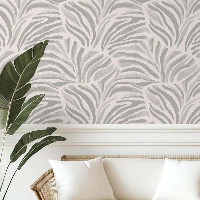 May include: A white and gray wallpaper with a zebra stripe pattern. The wallpaper has a watercolor effect and is shown on a wall in a room with a white couch and a green plant.