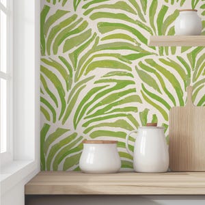 May include: A kitchen countertop with a green and white patterned wallpaper featuring abstract leaf designs. There are three white ceramic containers on the countertop, two with lids and one without.