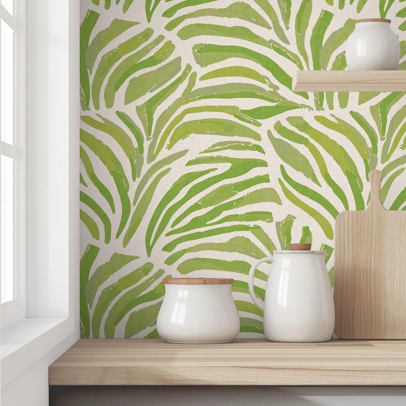 May include: A kitchen countertop with a green and white patterned wallpaper featuring abstract leaf designs. There are three white ceramic containers on the countertop, two with lids and one without.