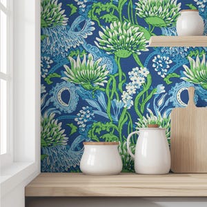 May include: A blue and green floral wallpaper with a white ceramic jar and pitcher on a wooden shelf.