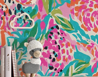 Puede incluir: Un colorido estampado floral en rosa, naranja, turquesa y verde domina el fondo. Un peluche de llama gris con gorro y bufanda blancos descansa sobre una estantería de madera. También hay decoraciones de madera en forma de nube y estrella, junto con dos libros.