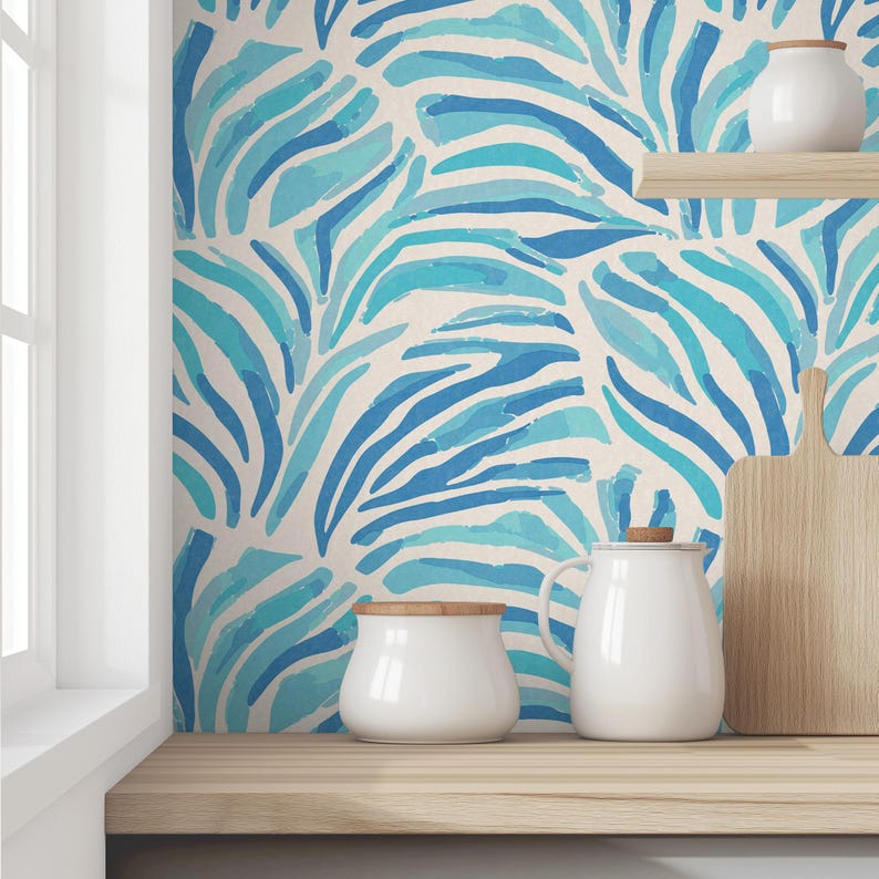 May include: A kitchen countertop with a blue and white watercolor zebra print wallpaper. There are three white ceramic containers on the counter, including a pitcher, a jar with a wooden lid, and a smaller jar.