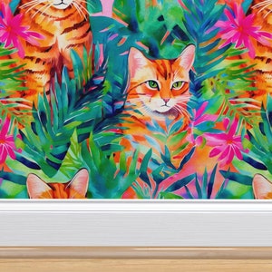 May include: Three orange tabby cats are hidden in a jungle of vibrant green and pink tropical leaves. The cats are peeking out from behind the leaves, with only their heads and shoulders visible.