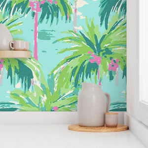 May include: A teal, green, and pink tropical palm tree wallpaper with a white pitcher and a small jar on a wooden coaster.