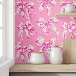 May include: Pink wallpaper with a white bow pattern. Two white ceramic containers and a wooden cutting board are on a wooden countertop.