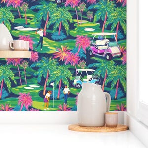 May include: A vibrant, tropical-themed wallpaper featuring a golf course scene. The design includes palm trees, golf carts, and golfers in action, with a color palette of green, blue, pink, and white. The wallpaper is displayed behind a white pitcher, a small cup, and a wooden coaster.
