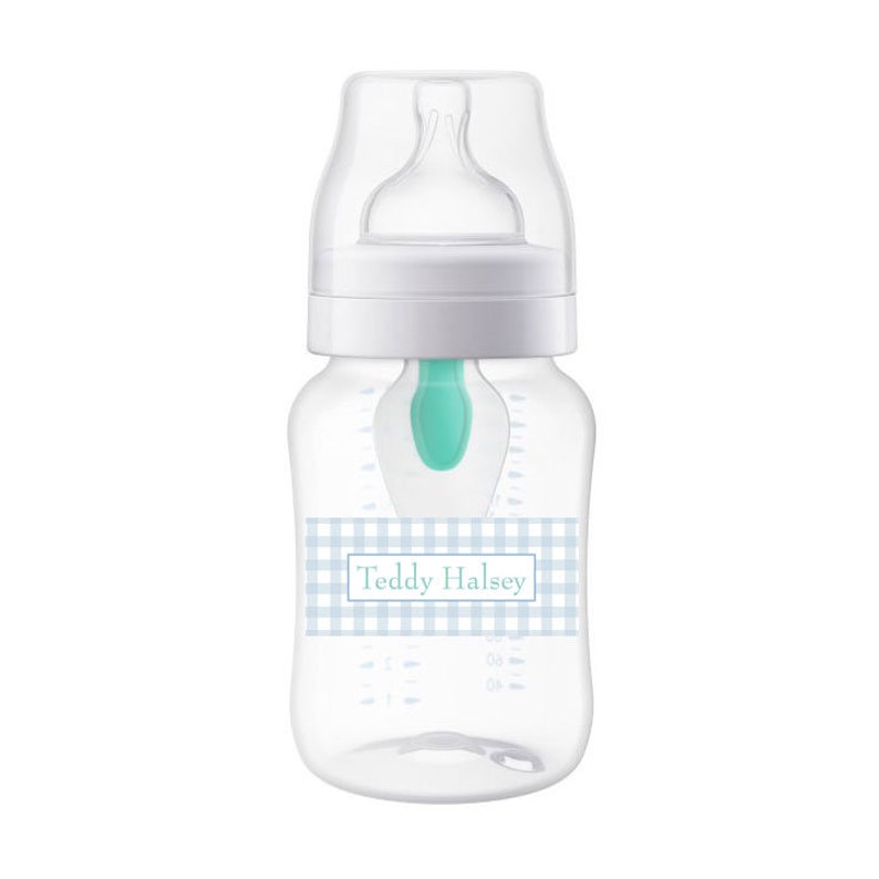 May include: A clear baby bottle with a white lid and a blue and white checkered label that says "Teddy Halsey".
