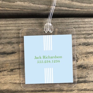 May include: A clear plastic luggage tag with a light blue background and white stripes. The text "Jack Richardson 555.234.1234" is printed in green.