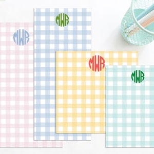 May include: Four different gingham patterned notepads with a monogram in the center of each. The notepads are pink, blue, yellow, and green.