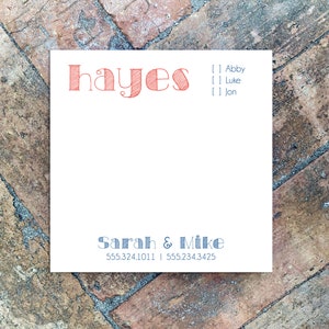 May include: A white notepad with the name "hayes" in red script at the top. Below, the names "Sarah & Mike" and two phone numbers are printed in blue. The background is a brick pattern.