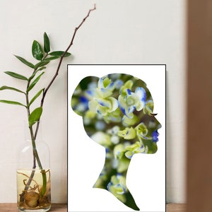 Op de afbeelding: Een zwart silhouet van een hoofd en schouders van een persoon met een bloemenpatroon erin. De bloemen zijn wit met blauwe randen en scherp in focus. De achtergrond is wit.