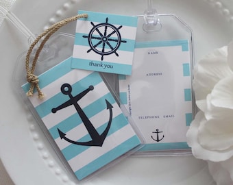 May include: Clear plastic luggage tags with nautical-themed inserts. One tag features a black anchor on blue and white stripes. Another has a ship's wheel design. A smaller tag says "thank you". The tags have a beige rope for attachment.