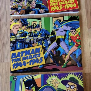 May include: Three Batman: The Dailies comic book collections featuring colorful illustrations of Batman and Robin. The covers are titled 1943-1944, 1944-1945, and 1945-1946, showcasing various villains and action scenes in a classic comic book art style.