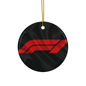 May include: A circular black ornament featuring the red F1 logo. The logo is a stylized design of the number one and the letter F. It hangs from a gold string, suitable for festive decorations.