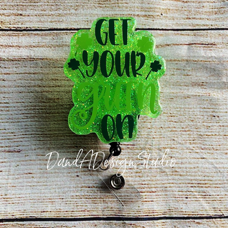 May include: Green glitter badge holder with a black retractable reel. The badge holder has a green shamrock design and the text "Get Your  Grin On".
