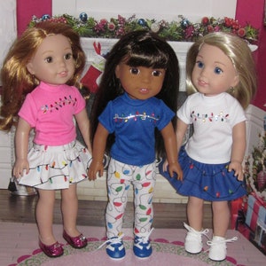 May include: Three dolls wearing Christmas light themed outfits. The doll on the left is wearing a pink shirt with a white skirt with colorful Christmas lights. The doll in the middle is wearing a blue shirt with white pants with colorful Christmas lights. The doll on the right is wearing a white shirt with a blue skirt with colorful Christmas lights.