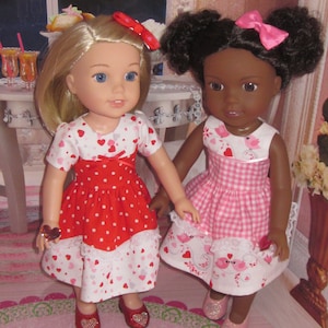 May include: Two dolls wearing red and pink dresses with white polka dots and hearts. The dolls are wearing red and pink shoes. The dolls are standing on a pink and green rug.