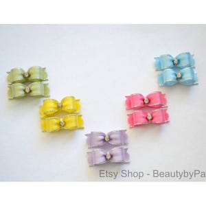 May include: Set of ten miniature satin ribbon bows with rhinestone centers. The bows are in five colors: light green, yellow, light blue, pink, and lavender.