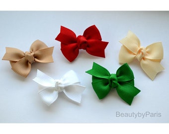 May include: Five small fabric hair bows in different colors: red, beige, white, green, and cream. The bows are tied with a knot in the center.