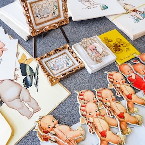 Lote de muñecas Kewpie vintage coleccionables, dos libros pequeños, postales navideñas, dos cuadros en miniatura con caballete, papelería y carta de Rosie O'Neill.