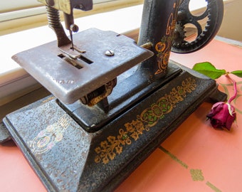 Antigua máquina de coser infantil francesa de hierro fundido "Bebé" con decoración de calcomanías de oro verde en la base y brazo de máquina de coser Era Art Déco gira