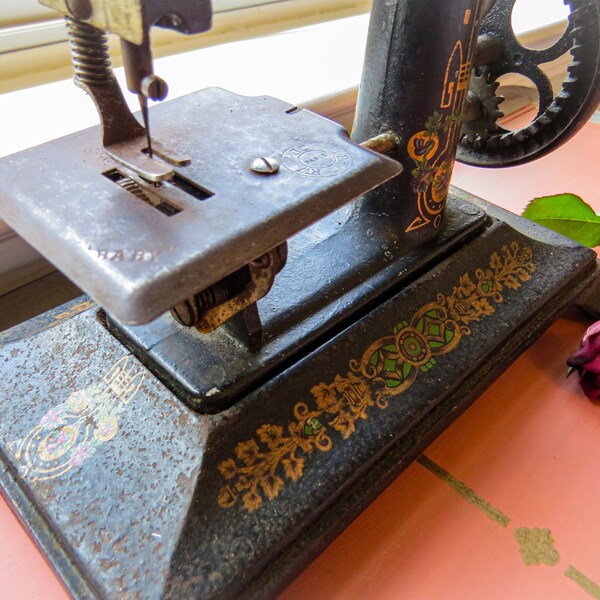 Ancienne machine à coudre pour enfant, France, en fonte, « Bébé » avec sticker décoratif doré vert sur la base et bras de machine à coudre époque Art déco tournant