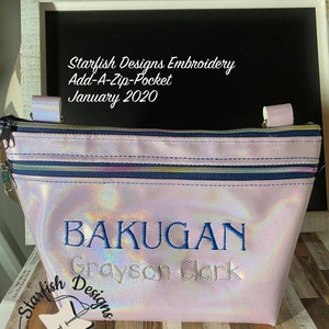 Puede incluir: Una bolsa rosa iridiscente con cremallera con un diseño bordado en azul que dice "BAKUGAN Grayson Clark" y el texto "Starfish Designs Embroidery".