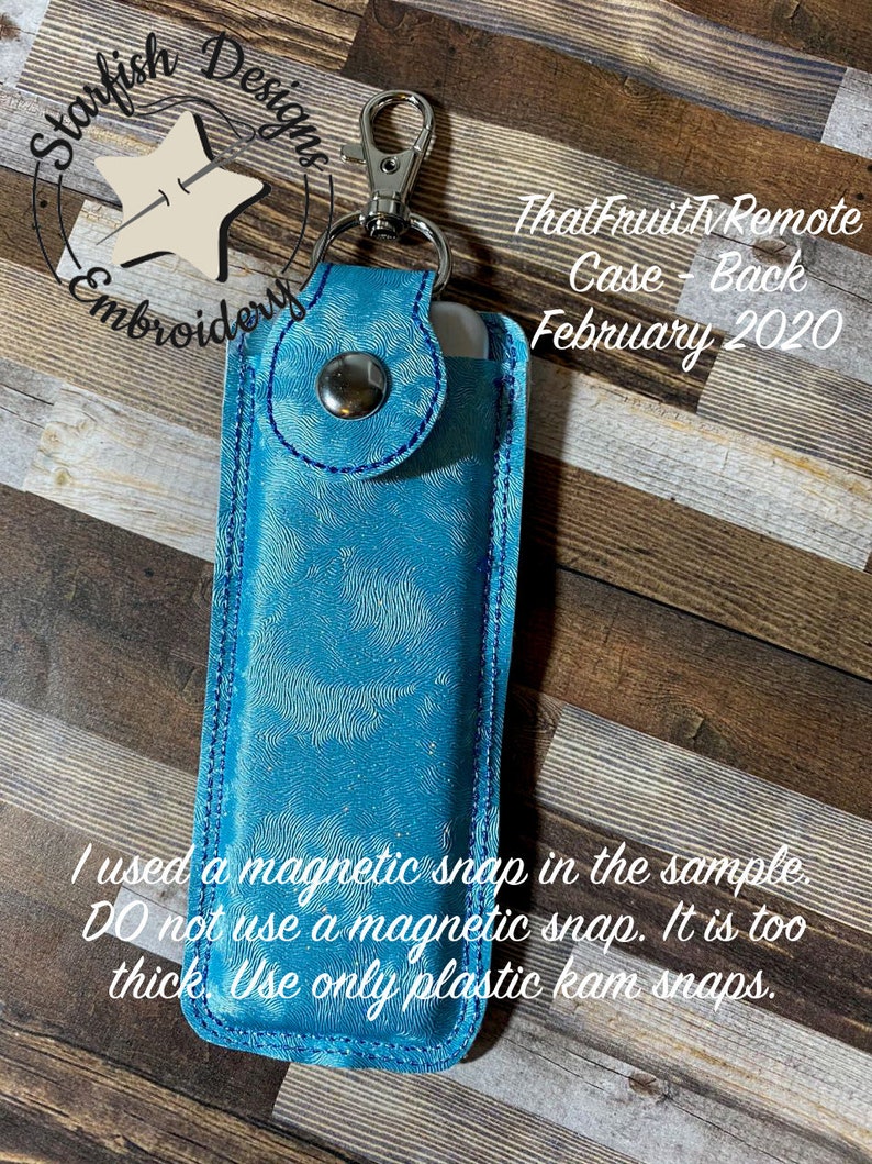 Pode incluir: Uma capa de couro azul turquesa com fecho de press&atilde;o prateado e um chaveiro prateado. A capa &eacute; para um controle remoto de TV e tem o texto "ThatFruit Tv Remote Case - Back February 2020" impresso nela. O texto "I used a magnetic snap in the sample DO not use a magnetic snap. It is too thick. Use only plastic kam snaps." est&aacute; impresso abaixo da capa.