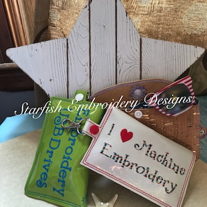 May include: Two green and white zippered pouches with the text "Embroidery" and "USB Drives" on them. A white pouch with the text "I Love Machine Embroidery" and a red heart. All pouches are on a white surface with a white starfish.