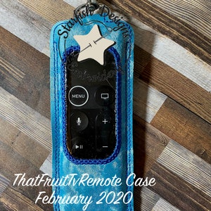 Pode incluir: Uma capa de controle remoto bordada em azul e branco com um design de estrela e o texto "ThatFruitTv Remote Case February 2020 *Requires 5x7 Hoop".