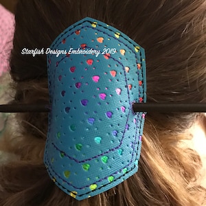 May include: A turquoise blue hair clip with a rainbow heart pattern and the text "Starfish Designs Embroidery 2019".