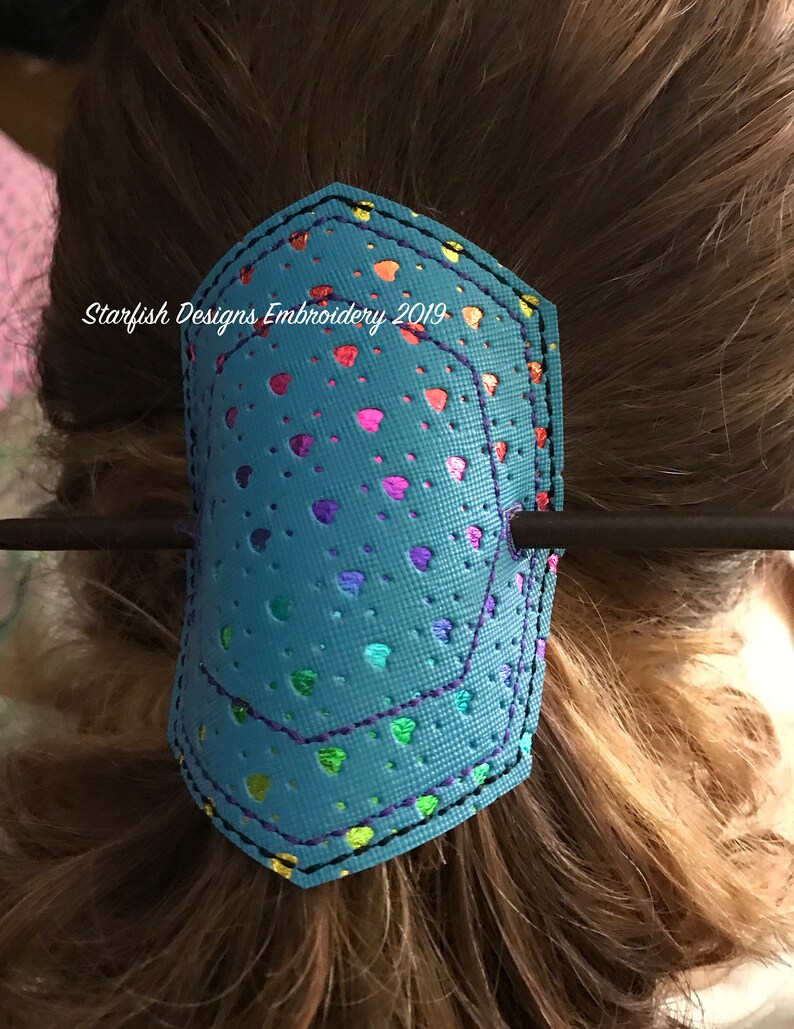 May include: A turquoise blue hair clip with a rainbow heart pattern and the text "Starfish Designs Embroidery 2019".