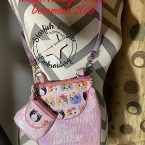 May include: A pink iridescent clutch purse with a cat print and a matching smaller coin purse. The purse has a purple strap and a zipper closure. The text "Midge Vintage Clutch December 2019" and "Starfish Designs Embroidery" is visible on the image. The text "7.9 x 7.9 & 4 x 4" is also visible.