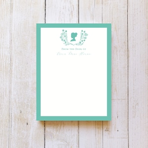 May include: A teal blue stationery notepad with a floral border and a silhouette of a woman's head. The text "From the Desk of" and the name "Theresa Marie Horne" are printed on the notepad.