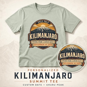 May include: A light sage green short-sleeve t-shirt featuring a graphic of Mount Kilimanjaro with the text "POLE POLE", "KILIMANJARO", "I SUMMITED", "UHURU PEAK 5,895 M / 19,341 FT", and "SEPTEMBER 14, 2026" printed in a circular badge design.