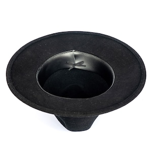 May include: A black fedora hat with a wide brim. The hat has a structured crown and a leather band inside. The hat is made of a felt-like material and is suitable for various occasions.