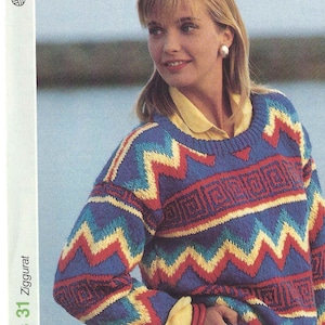 May include: A woman wearing a colourful knitted jumper with a geometric pattern. The jumper has a blue, red, yellow, and white colour scheme. The jumper is a zig zag pattern with a geometric design.