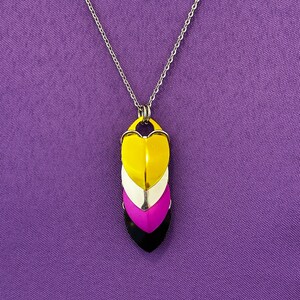 May include: A silver chain necklace with a pendant made of four stacked heart-shaped pieces. The hearts are yellow, white, purple, and black.