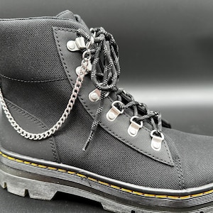 May include: Black canvas high-top boots with a silver chain detail and a yellow stitched sole.