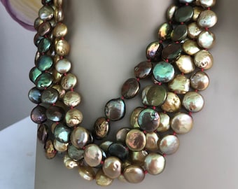 May include: A multi-strand necklace made of large, round, iridescent pearls in shades of green, brown, and gold. The pearls are strung on a red cord.