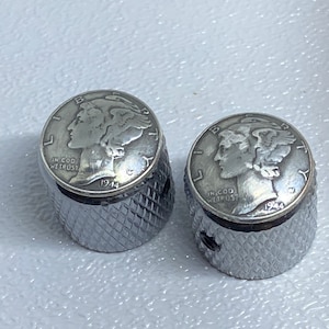 May include: Two silver guitar knobs with a 1944 Mercury dime design. The knobs have a knurled texture.