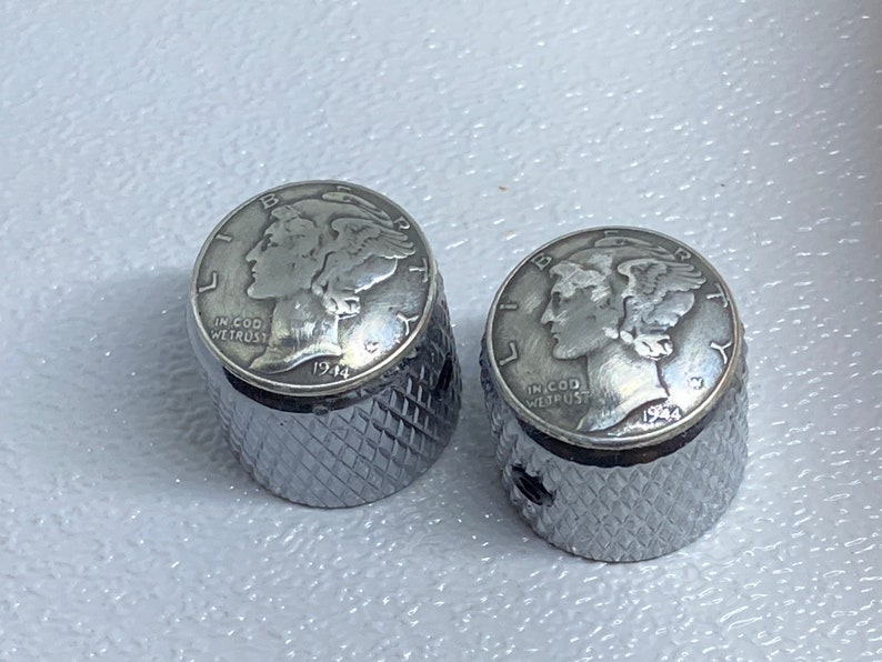 May include: Two silver guitar knobs with a 1944 Mercury dime design. The knobs have a knurled texture.