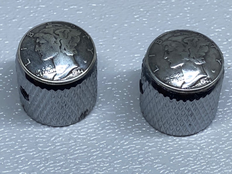 May include: Two silver guitar knobs with a 1944 Mercury dime design on top. The knobs have a diamond pattern on the sides.
