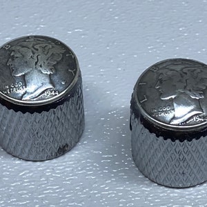May include: Two silver guitar knobs with a 1944 Walking Liberty Half Dollar coin design. The knobs have a knurled edge and a silver finish.