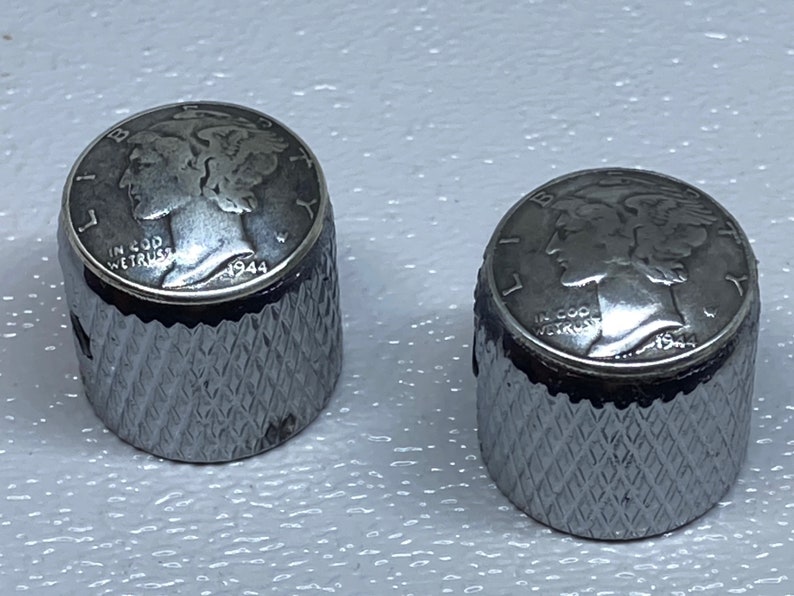 May include: Two silver guitar knobs with a 1944 Walking Liberty Half Dollar coin design. The knobs have a knurled edge and a silver finish.
