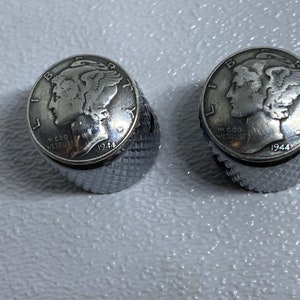 May include: Two silver-toned guitar knobs with a 1944 Mercury dime embedded in the top of each knob.