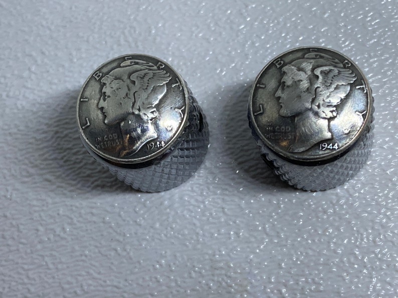 May include: Two silver-toned guitar knobs with a 1944 Mercury dime embedded in the top of each knob.