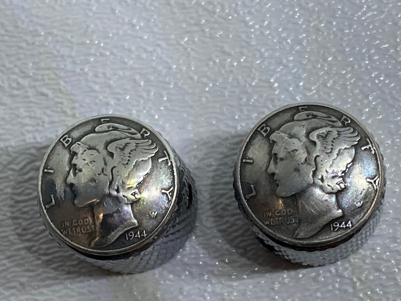 May include: Two silver-colored 1944 Walking Liberty Half Dollar coins. The coins are in good condition and have a slight patina.