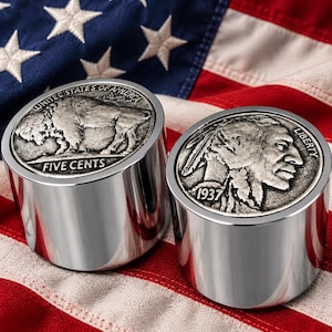 Op de afbeelding: Twee cilindrische metalen presse-papiers met ingebedde 1937 Buffalo nikkelmunten. De ene munt toont een bizon met de tekst UNITED STATES OF AMERICA en FIVE CENTS, de andere een profiel met de tekst LIBERTY en 1937.